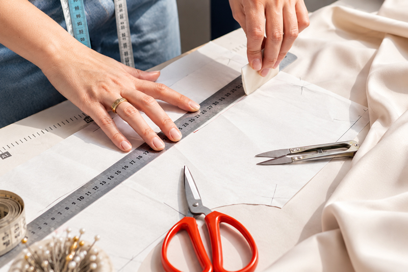 Traçage d'un patron de literie sur mesure à la règle, ciseaux de couture posés sur le tissu